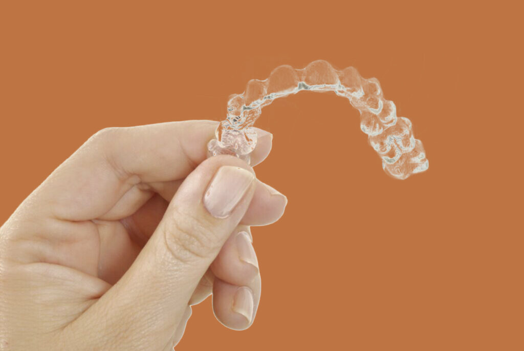 Hand holding a clear plastic dental retainer